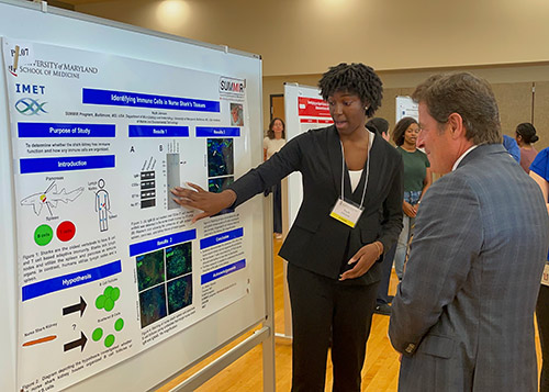 Najah Johnson explains her research poster to Dean Mark Gladwin